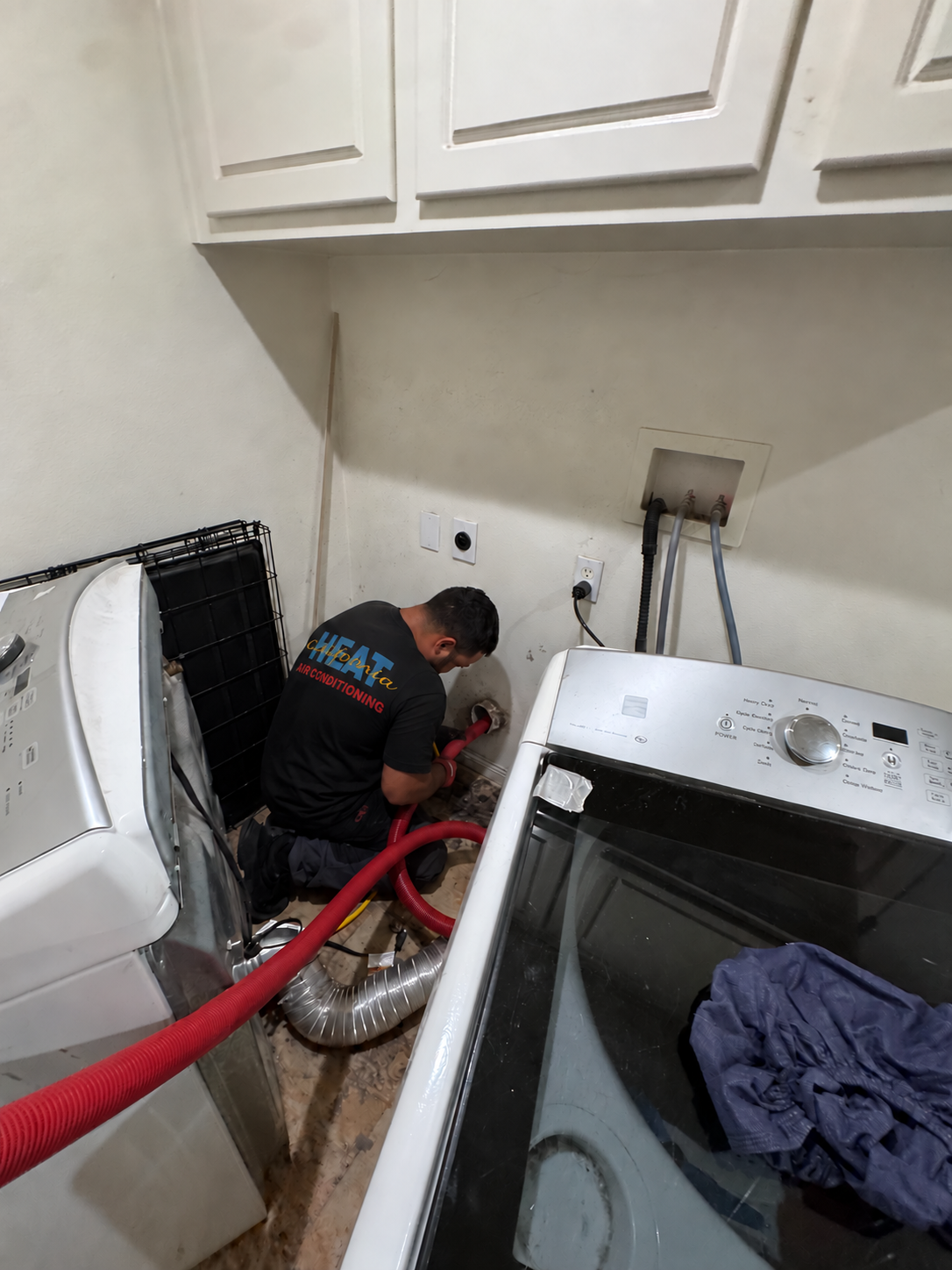 California Heat Air Conditioning technician using professional vacuum extraction equipment to clean a dryer vent line